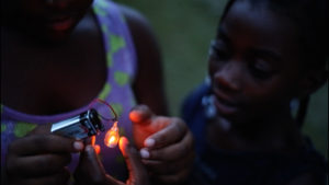 girl and mother holding light bulb and battery