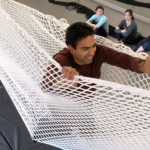 A student walks in a suspended net as other students watch from below