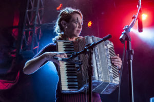 aurora plays accordion under blue red lights