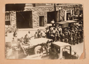 vintage trucks parked by stone building with crowds of people