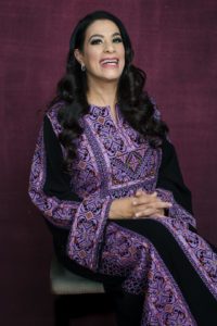 maysoon seated and smiling in long purple dress