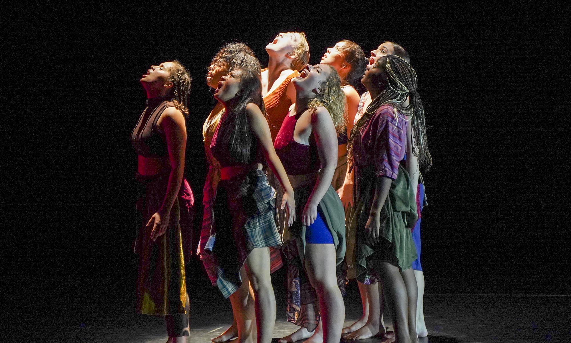 A group of 8 dancers stare upwards