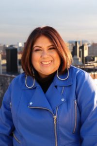 virginia smiling with short auburn hair and blue leather jacket