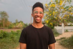 dexter thomas smiling in glasses and black tshirt outside by green plants