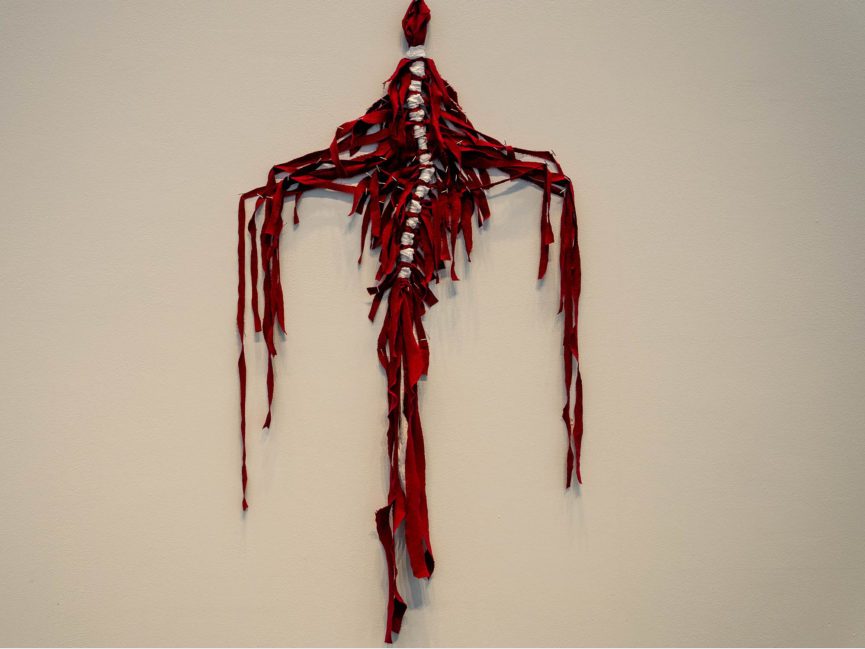 red textural sculpture hangs on wall