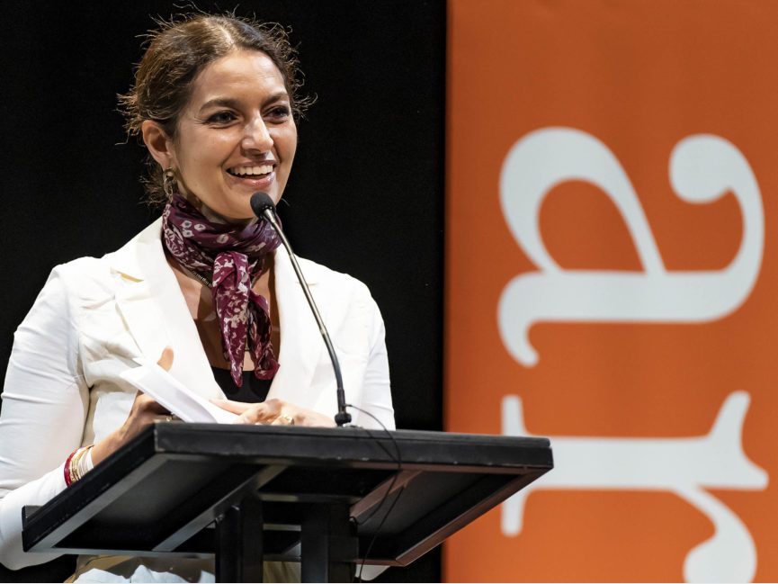 A person stands at a podium and talks into a mic