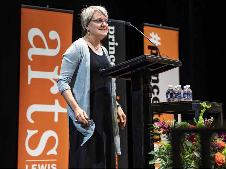 A person stands at a podium and talks into a mic