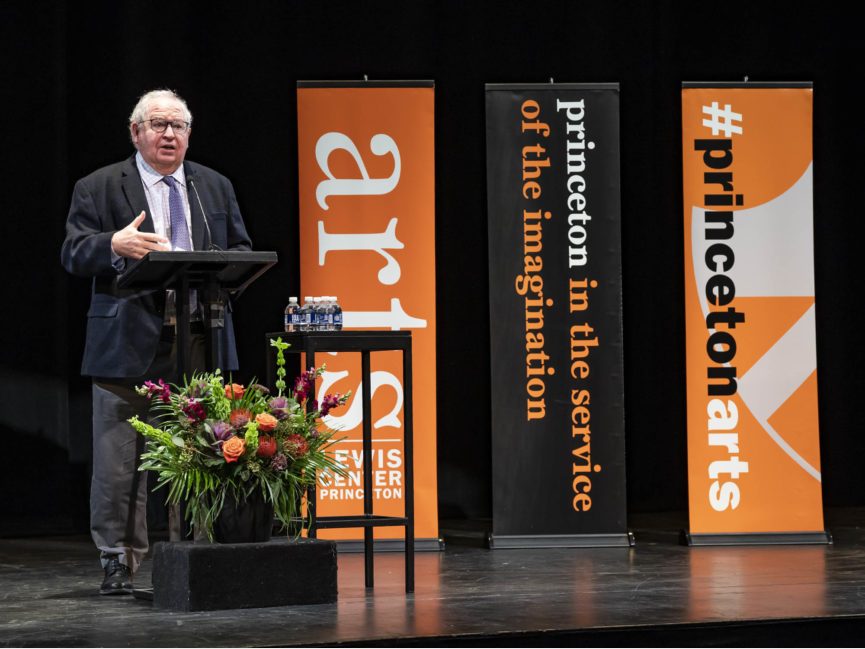 A person stands at a podium and talks into a mic