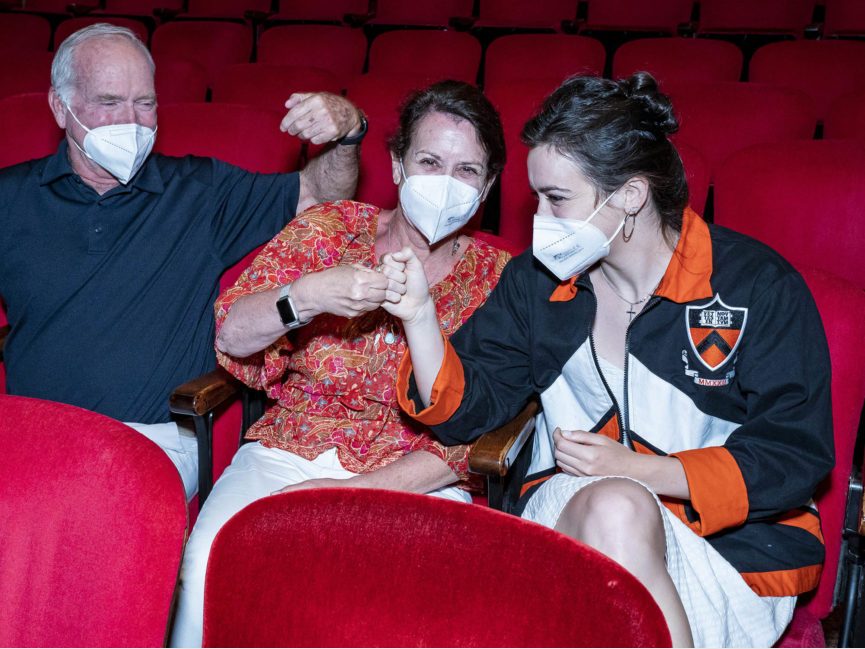 Three people bump fists in auditorium seats