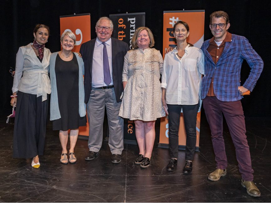 A group of people pose for a photo on a stage