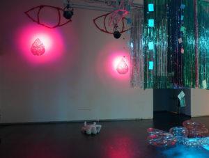 Giant pink eyes shed tears of pink disco balls on a gallery wall