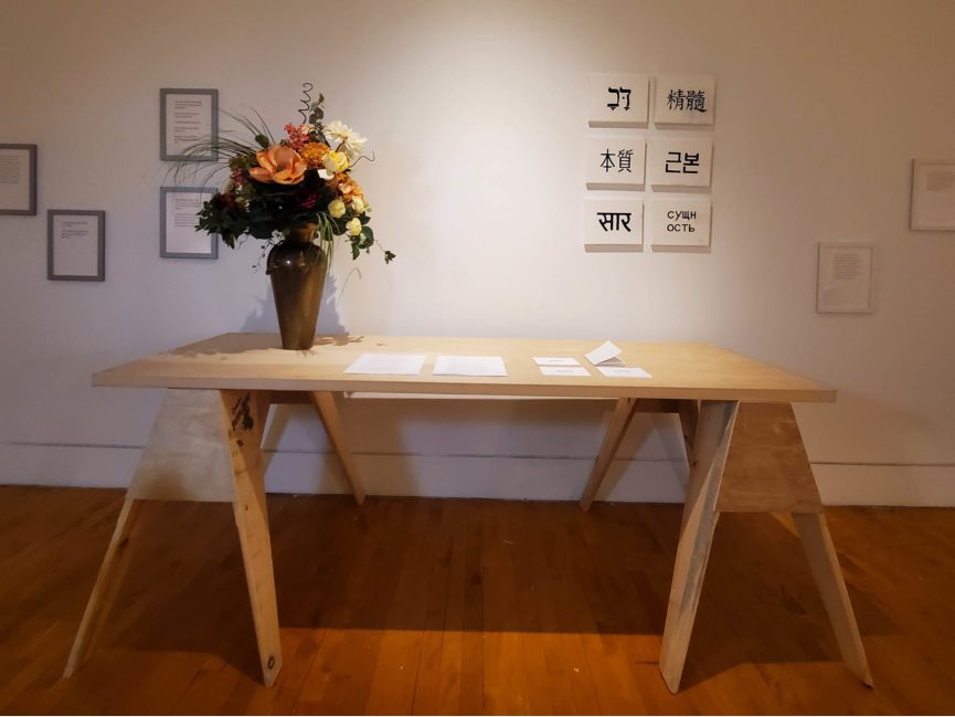 A vase of flowers on a table with framed artwork hanging on the wall