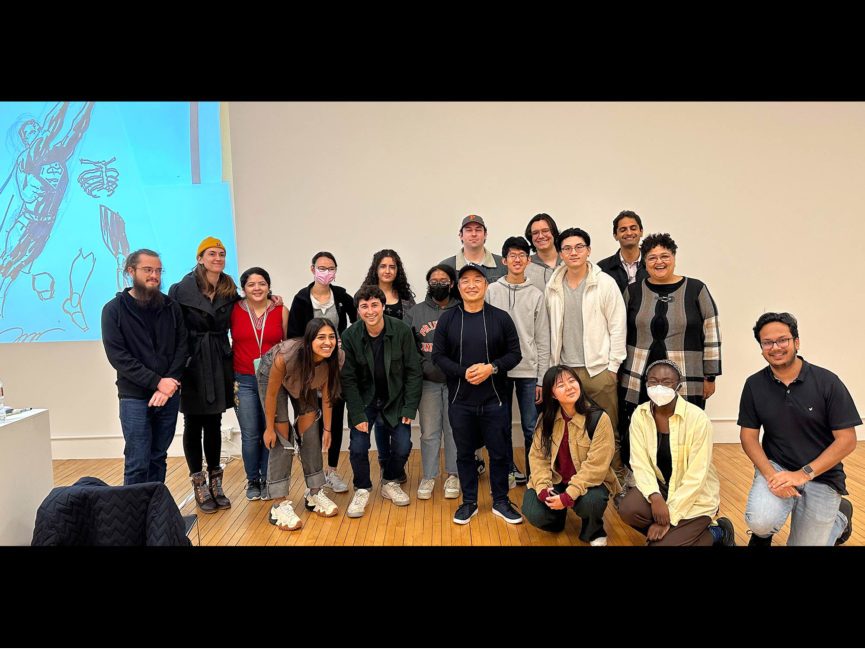 A group photo standing in front of an illustration of Superman