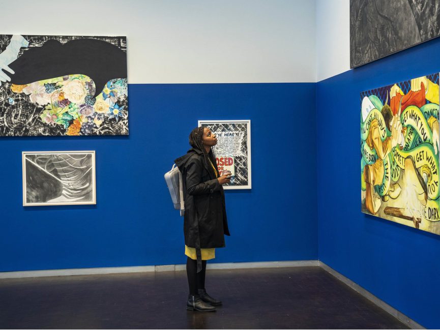 A person looks at paintings on a wall