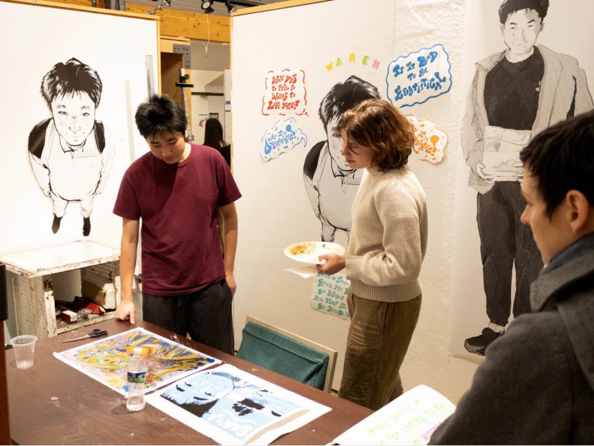 People mingle in a gallery pace surrounded by art hanging on walls