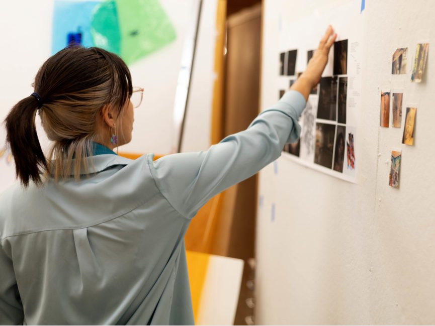 A student artist shows off artwork on a wall