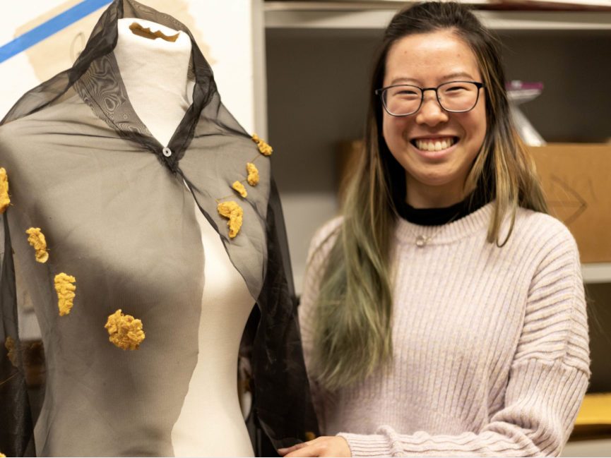 A student artist shows off work on a mannequin