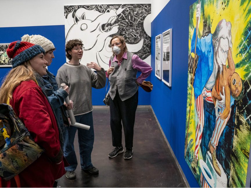 A group of people admire artwork on a gallery wall