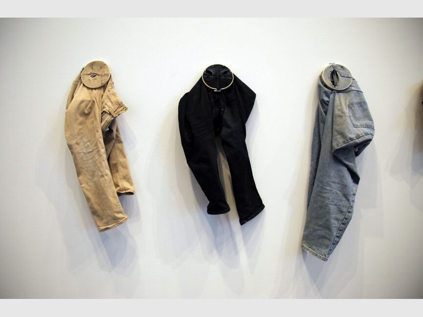 hanging on the wall are three pairs of altered pants with embroidery circles