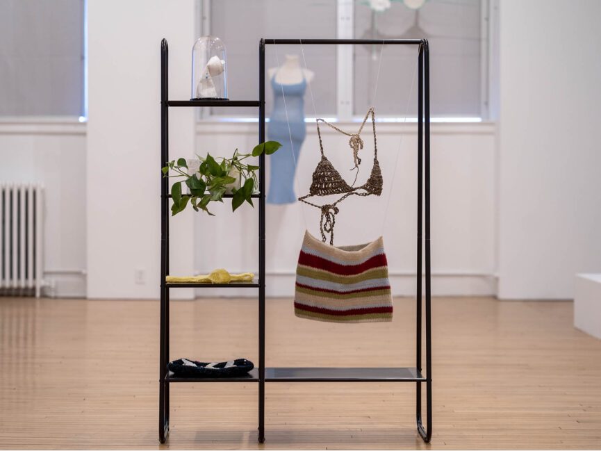 Various pieces of artwork hang on racks and rest on shelves in a gallery