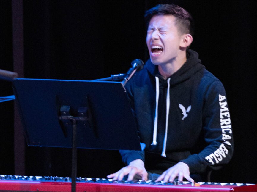 A performer sings and plays a keyboard at the same time.