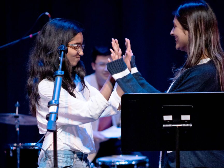 Two students high five each other on stage