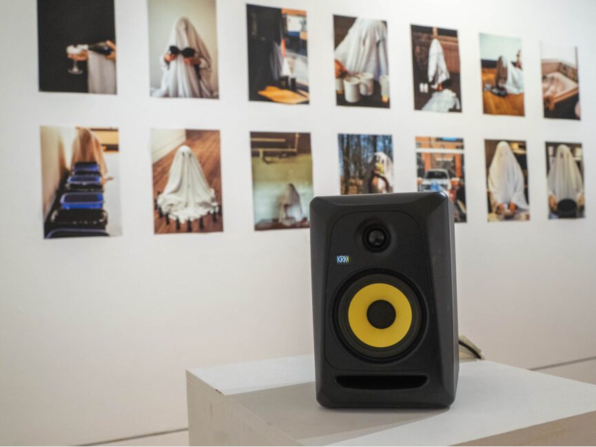 A speaker sits on a podium in front of photos of ghosts in different environments