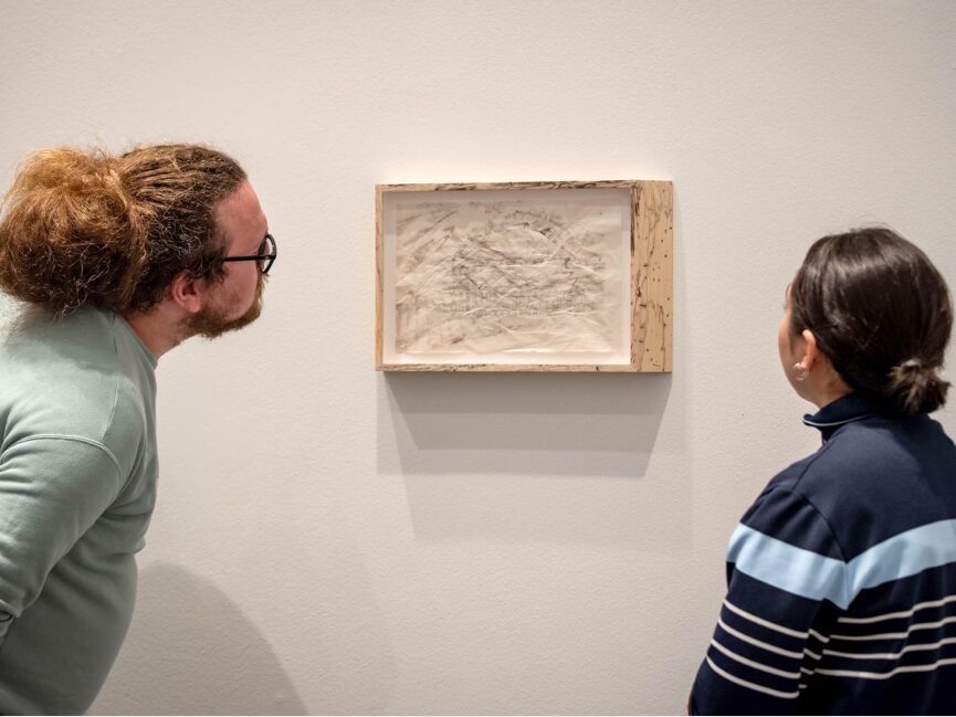 Two people look at artwork on a wall