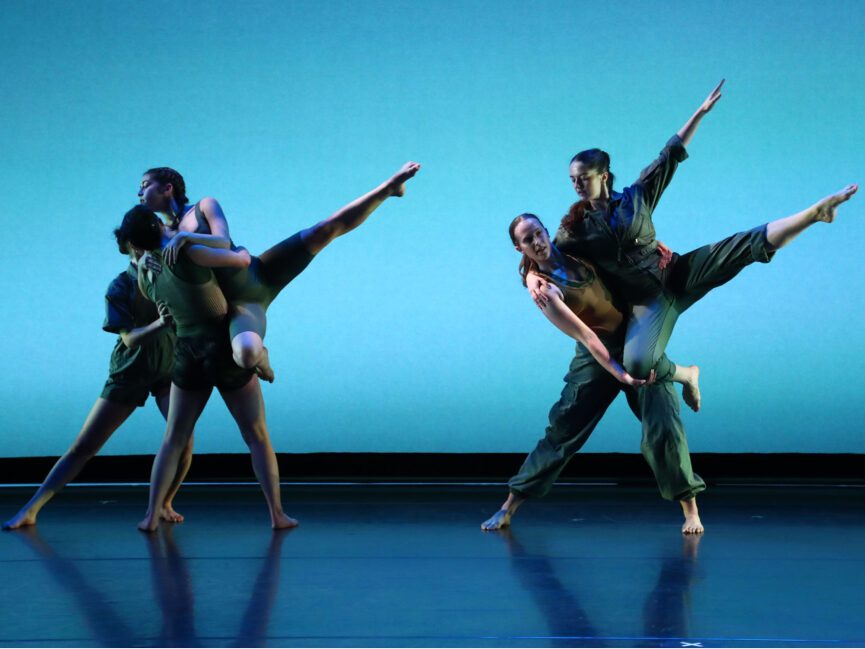 Two small groups of dancers hold each other in positions that display sharp angles downstage.