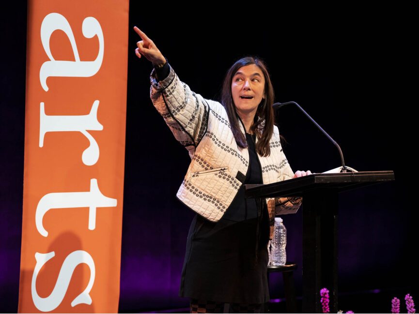 A poet stands at a podium with a book in hand