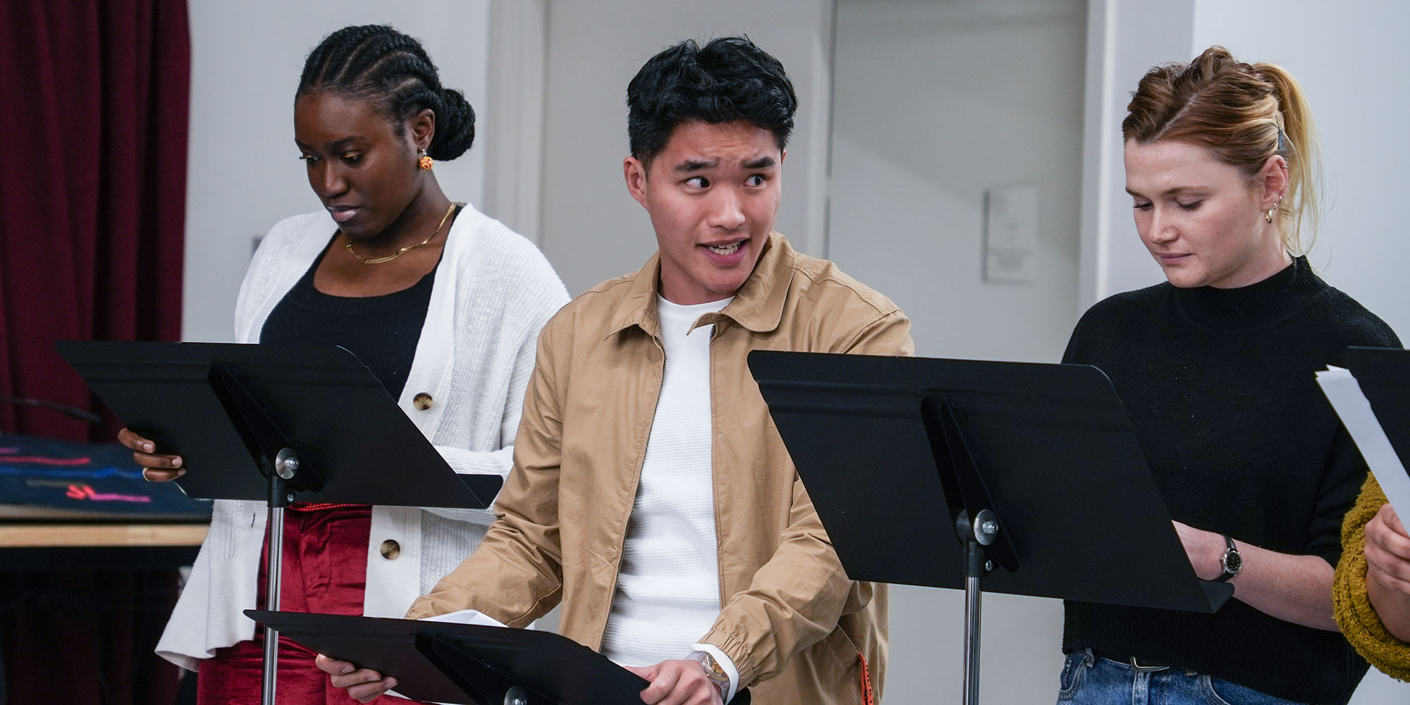 Three people read scripts on music stands