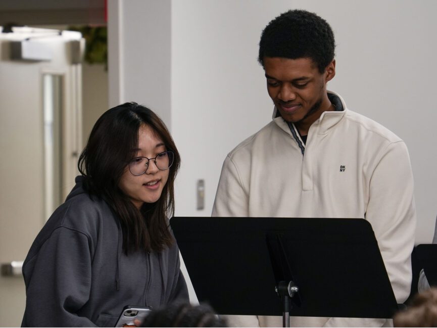 Two people read from a script at a music stand