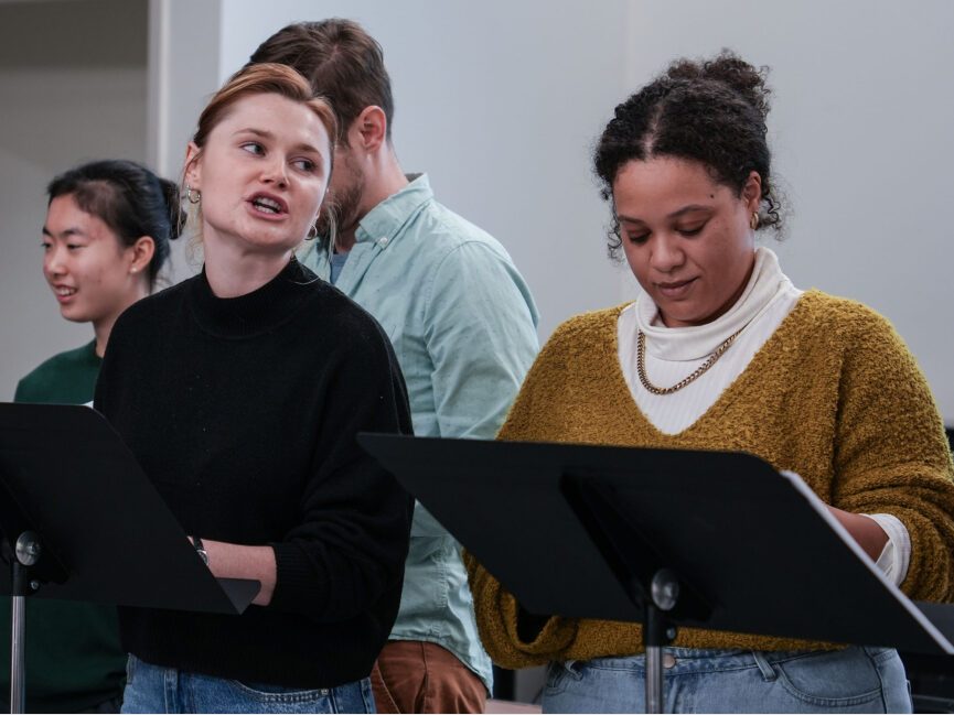 A group of people read from scripts on music stands