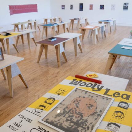 Sawhorse tables with artwork fill a gallery space.