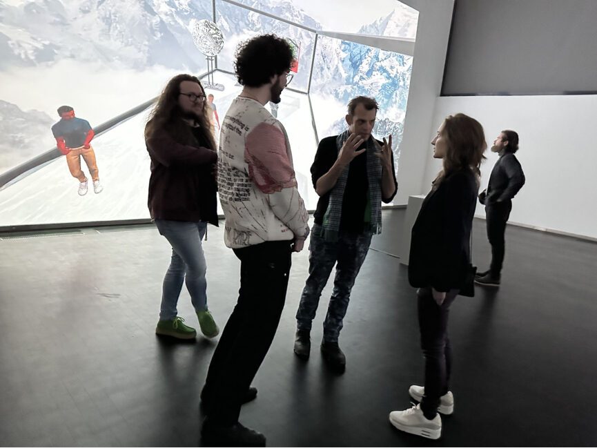 A group of people talk in front of a large projection