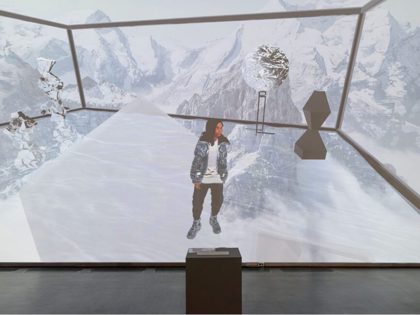 A keyboard on a podium sits in front of a large projection of an avatar in a virtual space