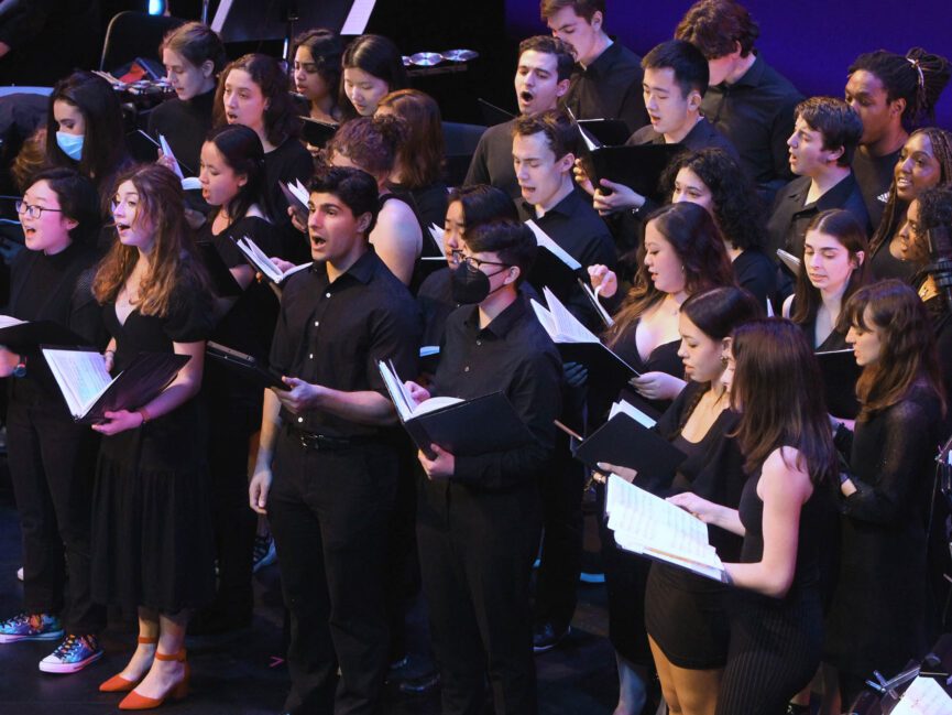 A chorus of people sing on stage