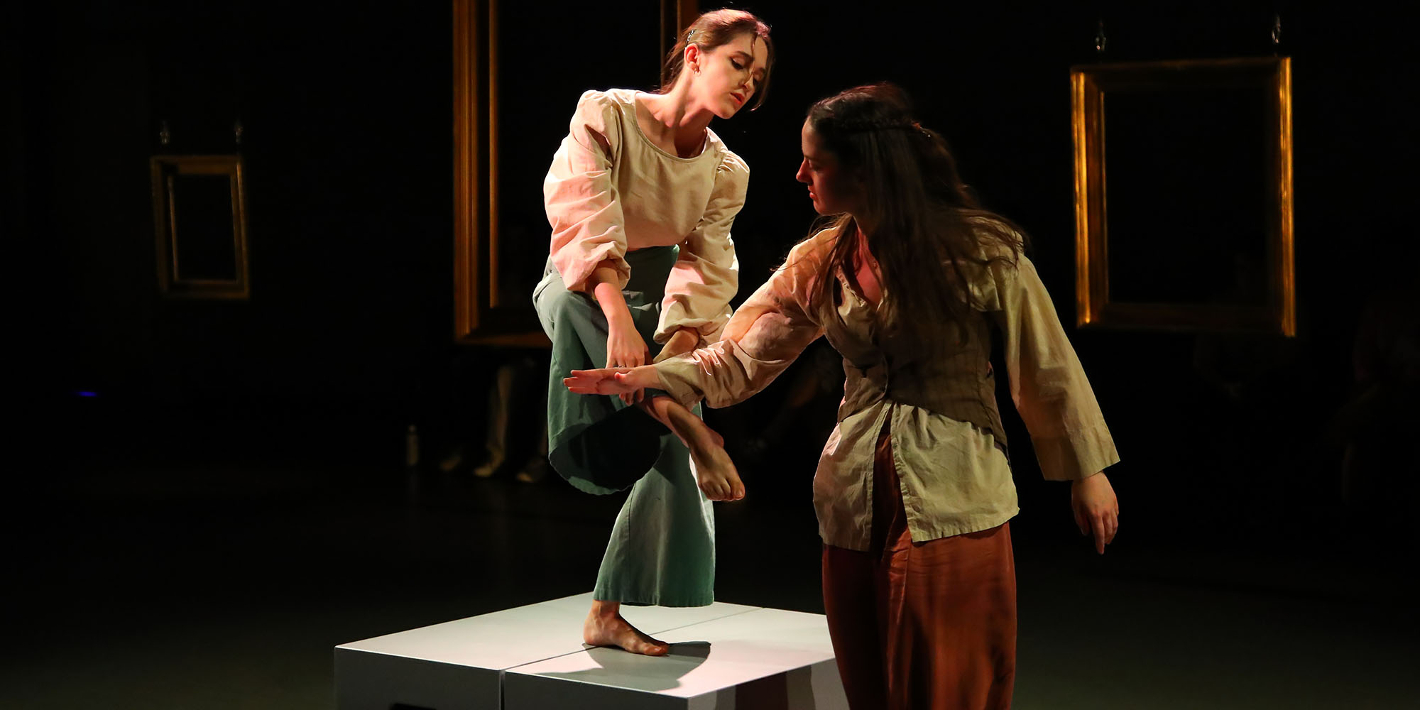 A dancer performs on a box with another dancer standing nearby