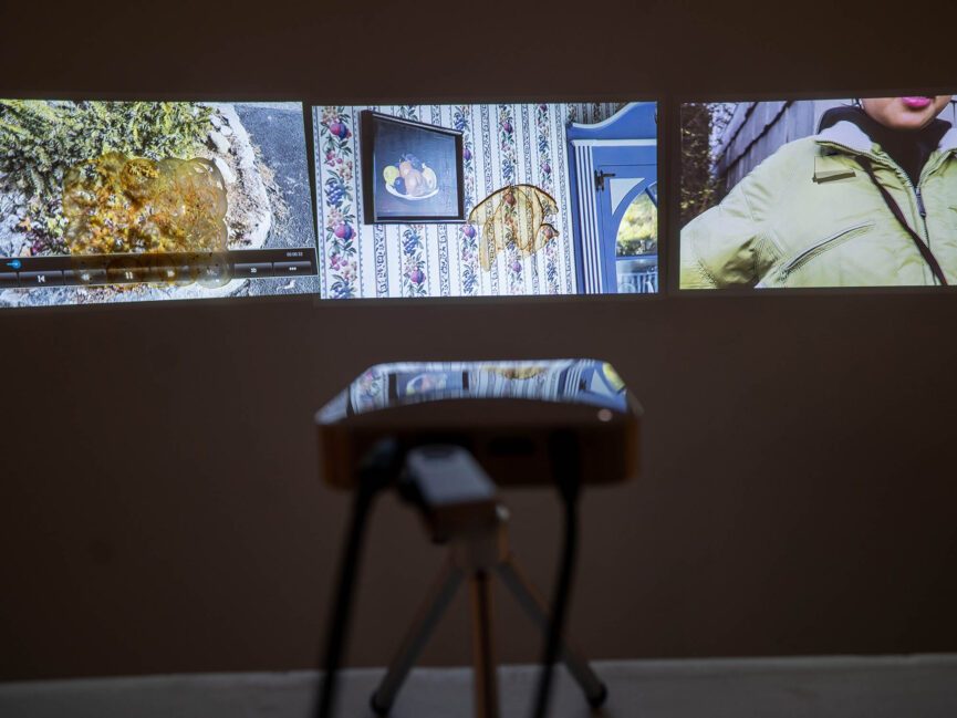 A projector sits in front of a wall displaying 3 separate projections