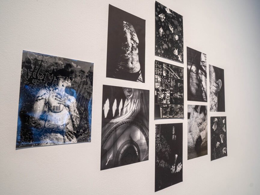 A series of black and white images are displayed on a wall of a gallery
