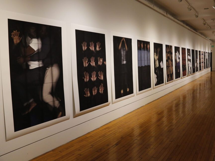 Photographic portraits hang on the wall of a gallery