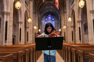 A student plays a violin in the main aisle of Princeton University Chapel