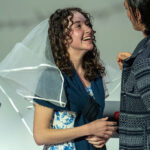 A performer looks up at another performer wearing a veil