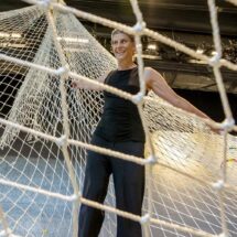 Rebecca Lazier stands in a net suspended from a stage ceiling