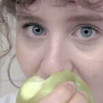 Juliette Carbonnier's face seen close up as she bites into a green apple.
