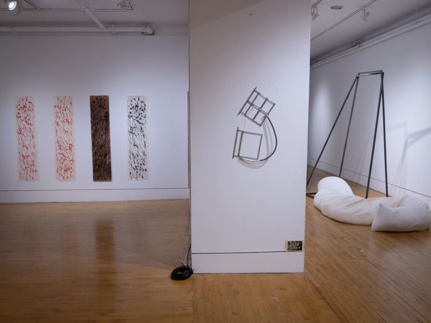 Artwork hangs on the walls and sits on the floor of a gallery