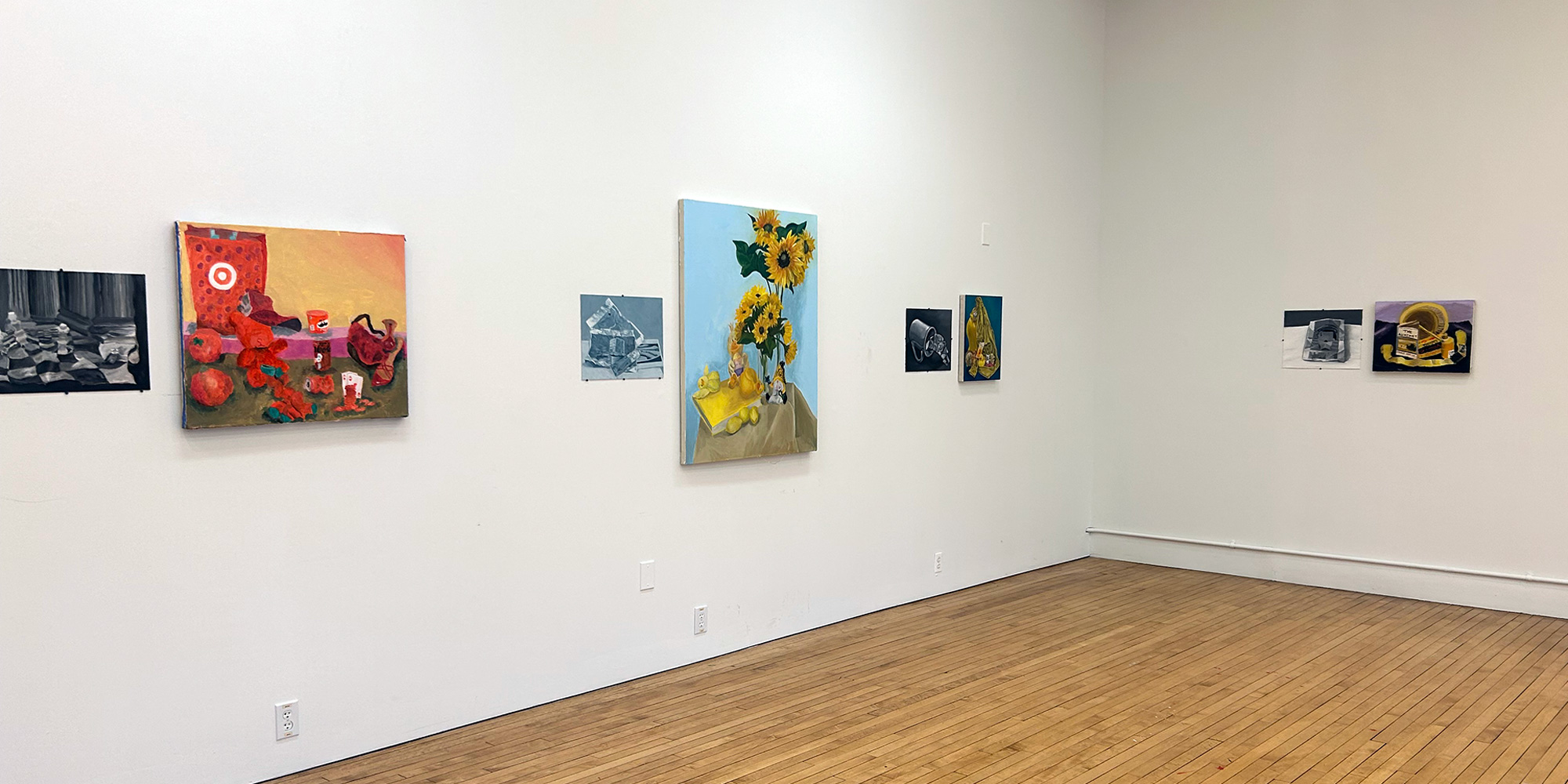 Several paintings arranged in groupings on white gallery wall.